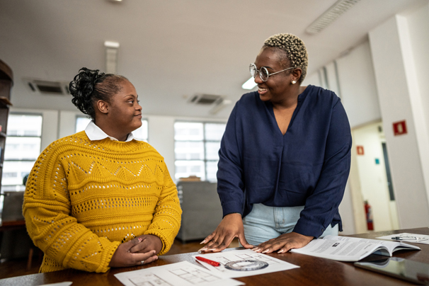 Young woman with Downs Syndrome talking with another woman.