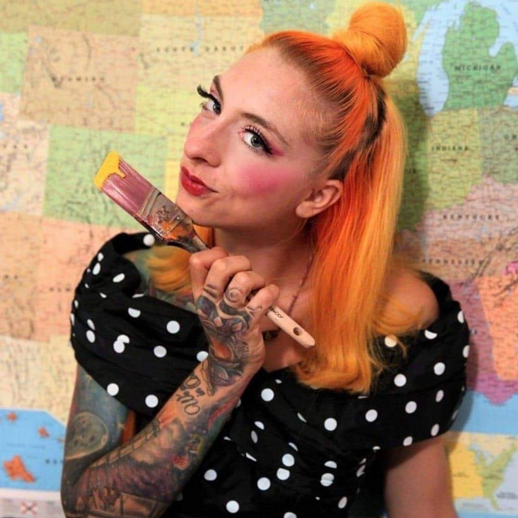 Woman in front of a map background holding a paintbrush.