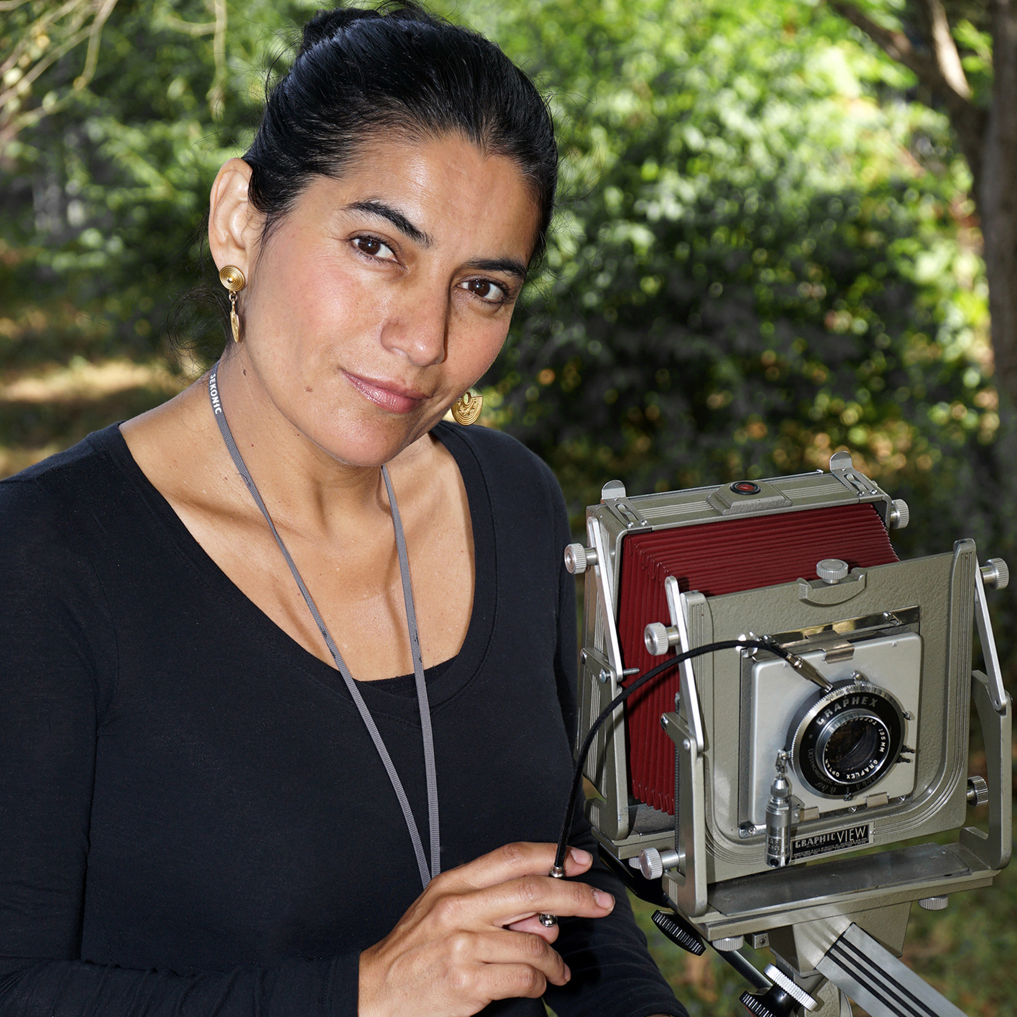 Photo of a woman smiling next to a camera.