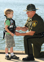 LEO assiting toddler with life jacket<br />