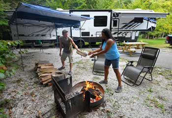 Two people feed wood to a fire