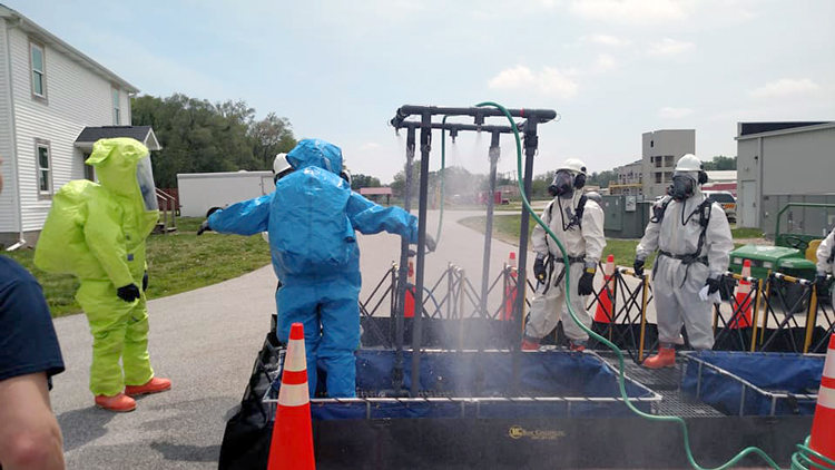 People in hazmat suits operating decontamination shower