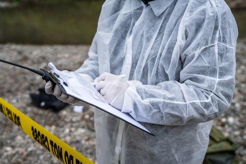 Person in protective suit writing on clipboard