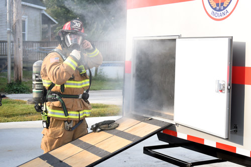 Firefighter adjusting mask before entering confidence training trailer