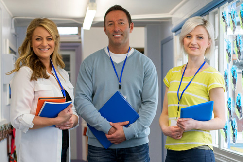 Teachers stand in hallway holding folders