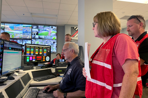 EOC personnel gather around computer screens in emergency operations center