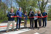 DNR Director Dan Bortner (far left), Gov. Holcomb, and Elkhart Mayor Rod Roberson (fourth from left) lead the ceremony marking the opening of the new section of the River Greenway Trail in Elkhart. (Photo by Stefan Welsh)