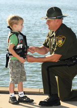 LEO assiting toddler with life jacket<br />        