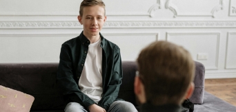 Young male sitting and talking with an adult.