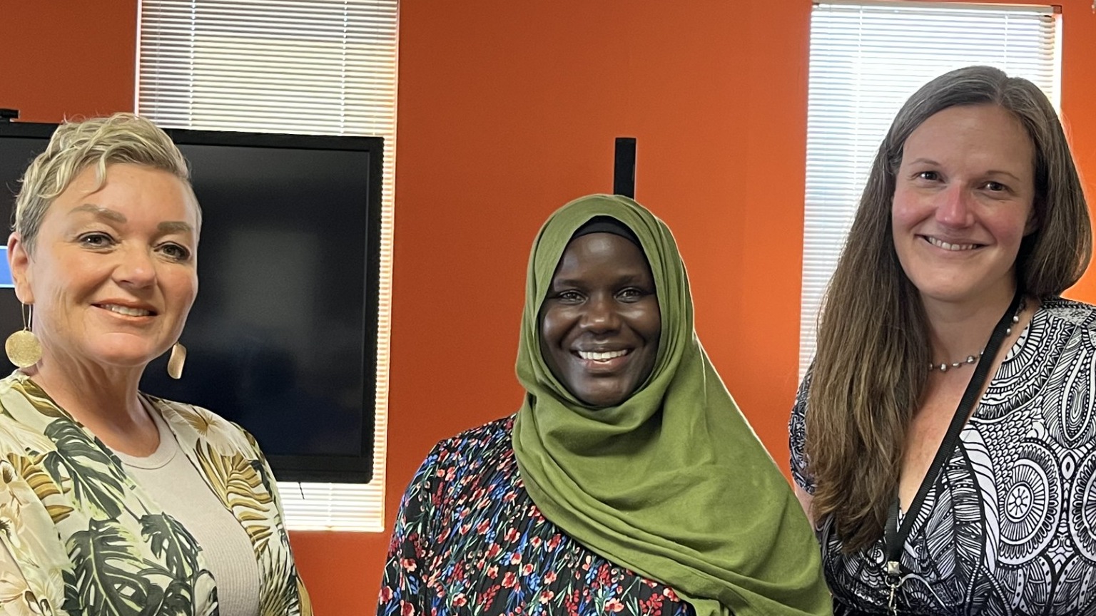 Three women with a projector screen in the background.