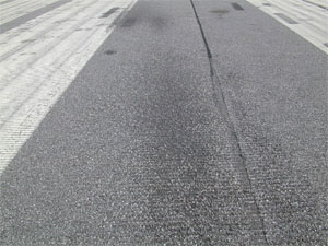 Photo showing a close-up area of a runway with a darkened surface due to jet-blast erosion.
