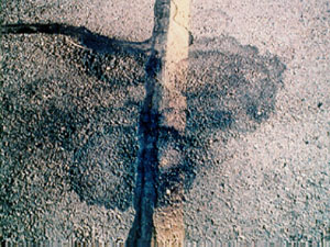 Photo showing a close-up small area with spilled oil on the pavement surface.