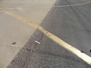 Overview photo showing a longitudinal joint between a PCC and an asphalt pavement.           The photo shows a slight amount of shoving of the asphalt for a short distance along the joint.