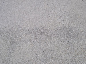 Close-up photo of a small area of asphalt pavement surface with a few missing pieces of aggregate.