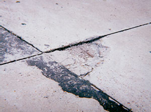 Close-up of a high-severity corner spall. The corner spall is highly deteriorated and shows signs of loose material.